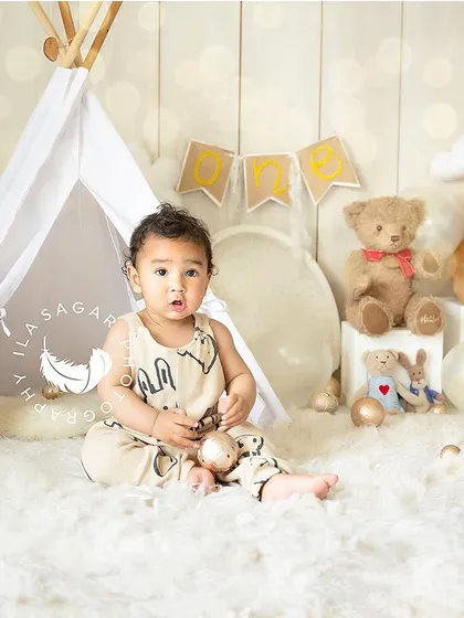 A classic portrait from a first-year milestone session. This baby is sitting up in a cozy tent-themed set, looking curiously at the camera.
