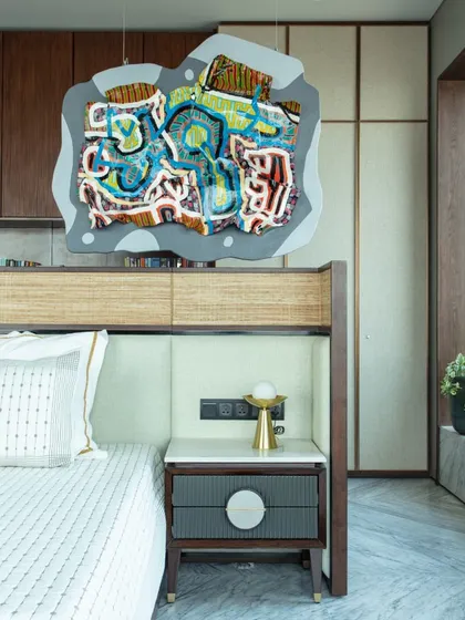 The daughter's bedroom is a dreamy retreat, centered around a leather and cane bed from Furgonomics. A vibrant hanging artwork by Bhuwal Prasad adds a splash of youthful imagination to the serene space.