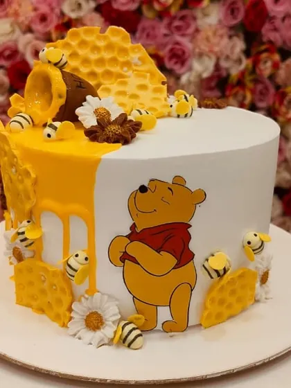 A sweet Winnie the Pooh cake, complete with a honey pot, edible bees, and honeycomb details. The half-and-half design is unique and visually interesting.