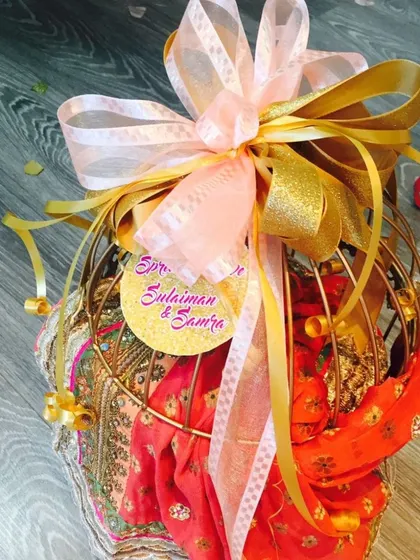 I love adding personal touches, like this custom tag with the couple's names. Here, a gift of colorful sarees is packed in a decorative birdcage-style basket, finished with a large, flowing ribbon.