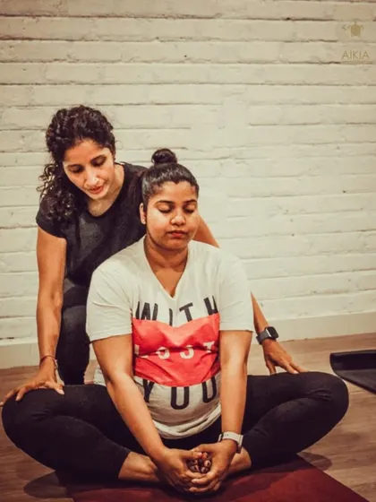 A teacher provides a gentle adjustment in Baddha Konasana (Bound Angle Pose) during a prenatal class. This hands-on support helps ensure proper alignment and maximizes the benefits of the pose.