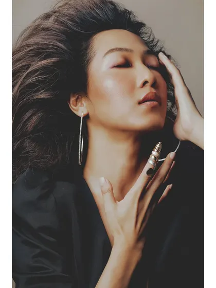 A serene and gentle portrait. The model's pose, with hands framing her face, and her soft expression create a sense of calm and introspection.