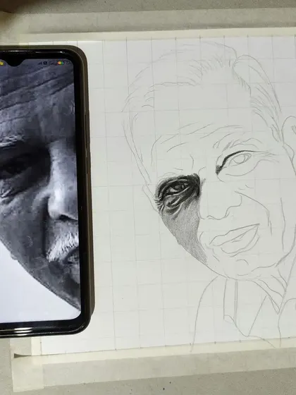 My process begins with precision. Here you can see how I use the grid technique, laying a grid over my paper to match the reference photo on my phone. This method ensures that the proportions and likeness of the final hand-drawn portrait are accurate from the very first line.