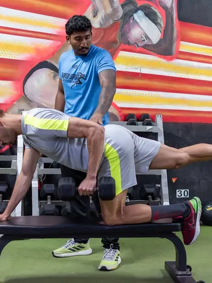 A coach provides feedback on a dumbbell row. Personalized attention ensures every client, regardless of level, is moving with correct technique.