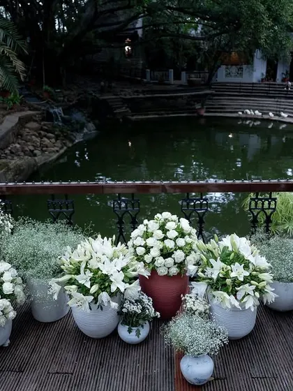 White floral arrangements in terracotta pots line the bridge over the Kalyani, blending rustic and elegant decor styles.