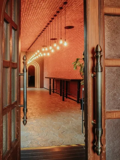 The entrance corridor welcomes guests with warm, dramatic lighting and exposed brick walls. This passage sets the tone for the experience within, creating a sense of anticipation.