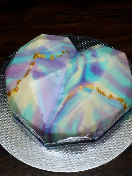 A heart-shaped mousse cake with a stunning mirror glaze finish. I created a marbled effect using pastel shades of purple, blue, and yellow, with touches of gold leaf for a truly artistic look.