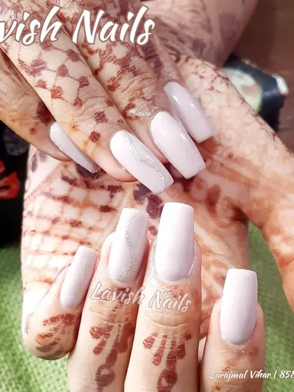 An elegant and subtle choice, these long, square-shaped nails in a soft, milky white polish look clean and sophisticated next to detailed bridal henna.