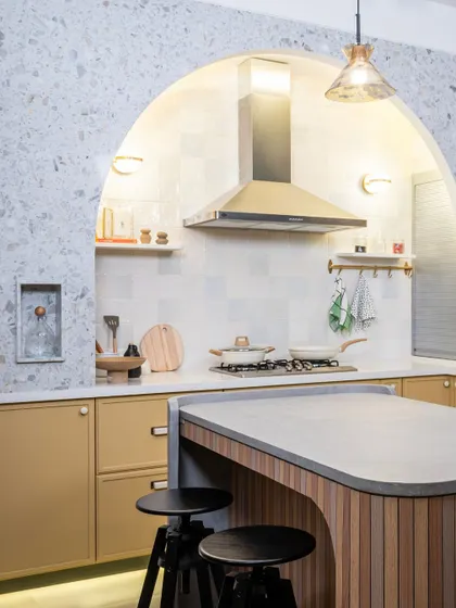 The arched cooking nook is the centerpiece of this kitchen. Lined with terrazzo, it creates a defined and elegant space for the hob and chimney, turning a functional area into a stunning focal point.
