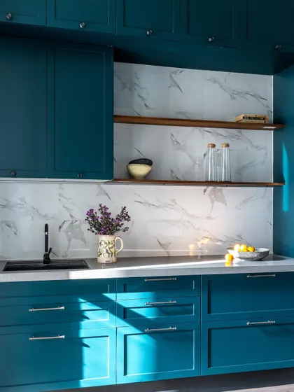 This kitchen from the Bombay Blue home is bold and embraces color. The deep teal cabinets and custom stained-glass arched door make a beautiful statement, nodding to old Bombay's Art Deco style.