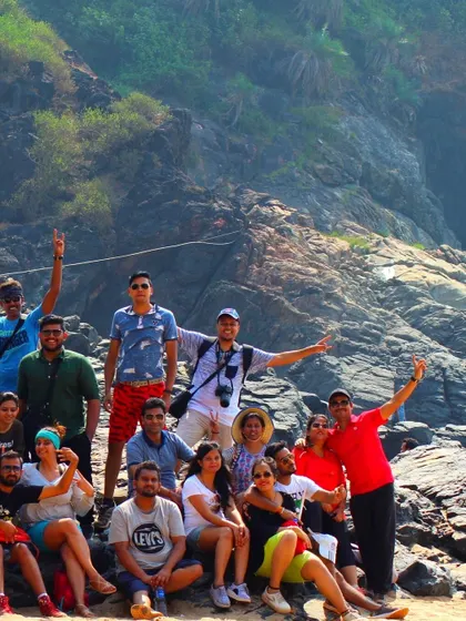 A team poses for a group photo on the rocks during the Gokarna beach trek, with the rugged coastline behind them.