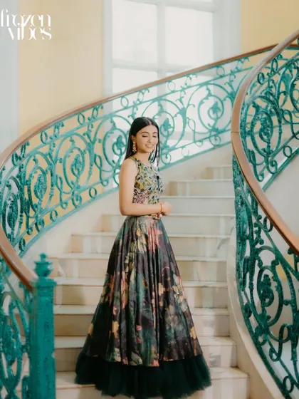 A beautiful solo portrait of the bride, Shikha, on a grand, winding staircase. The elegant setting complements her floral gown perfectly, creating a timeless and graceful image.