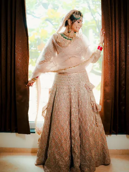 A full length portrait of a beautiful Sikh bride in a pastel lehenga, captured in natural light to showcase her elegance and the flow of her outfit.