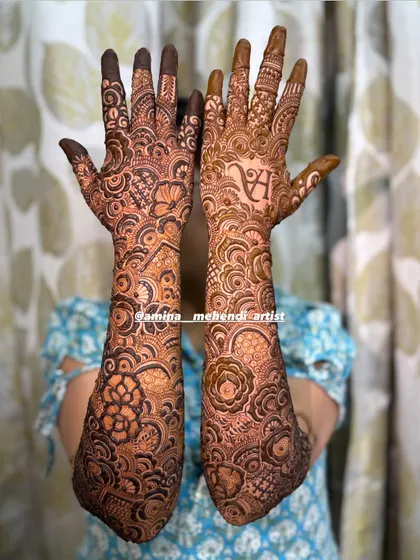 The full, two-arm view of the personalized mehendi with the initial 'H', showcasing the dense and elaborate floral work.