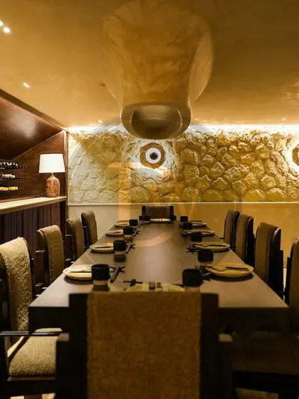 The private dining area at 'Call Me Ten', featuring a long, custom-built table and chairs designed by us. The furniture's clean lines and dark wood finish provide a sophisticated contrast to the textured, stone-like walls.