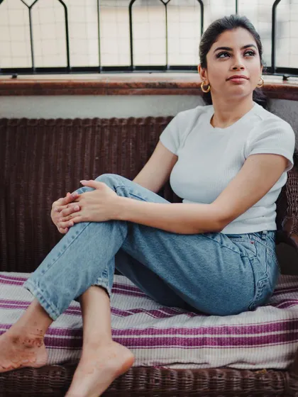 A relaxed, natural light portrait taken on a balcony. The simple white t-shirt and jeans combination makes this a timeless and authentic lifestyle shot.