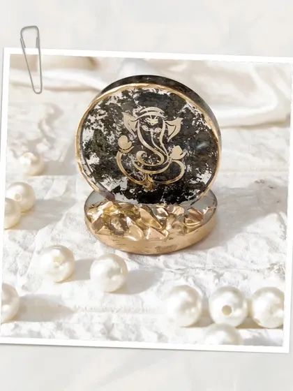 Bless your space with a divine touch. This customized mini Ganesh Ji stand features a black and gold design, surrounded by pearls. It's perfect for a car dashboard, office desk, or as a thoughtful gift.