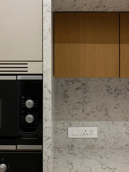 This detailed shot highlights the precise integration of the oven and the surrounding cabinetry. The combination of the textured quartz, the warm wood, and the clean lines of the appliance demonstrates a commitment to both beauty and function.