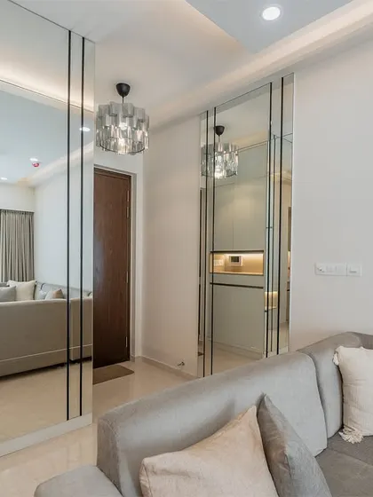 A full-length mirror wall is a powerful design tool. It not only makes the room appear double in size but also reflects light, making the entire living area feel more open and vibrant.
