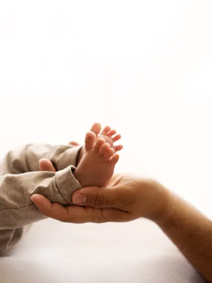 Tiny feet held securely in dad's hand. This shot emphasizes just how small and precious they are in these first few weeks. A classic newborn detail shot.
