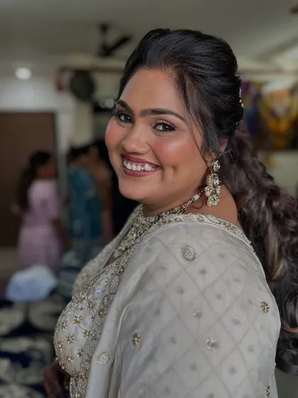A beautiful over-the-shoulder shot. The client's makeup is soft and radiant, with a focus on glowing cheeks and a defined eye.
