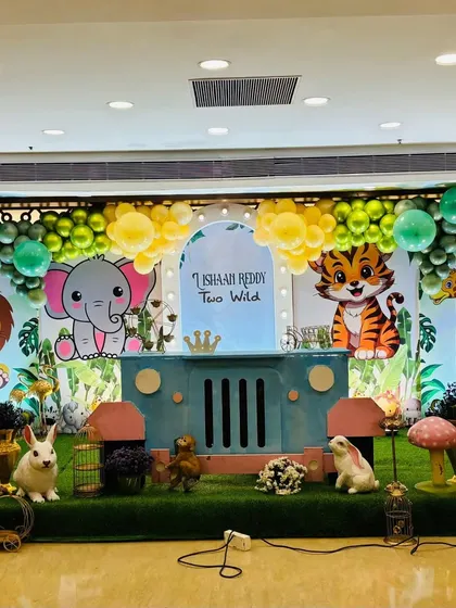 A centered view of the cartoon jungle animal stage, showcasing the backdrop with personalized text and balloon garlands.