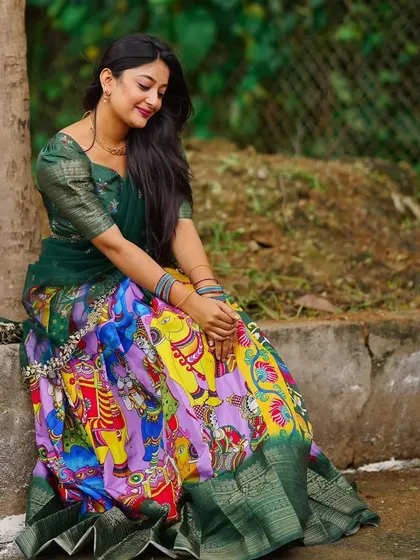 A client seated gracefully in a Kalamkari print Langa Davani. The artistic skirt is the highlight of this traditional outfit.