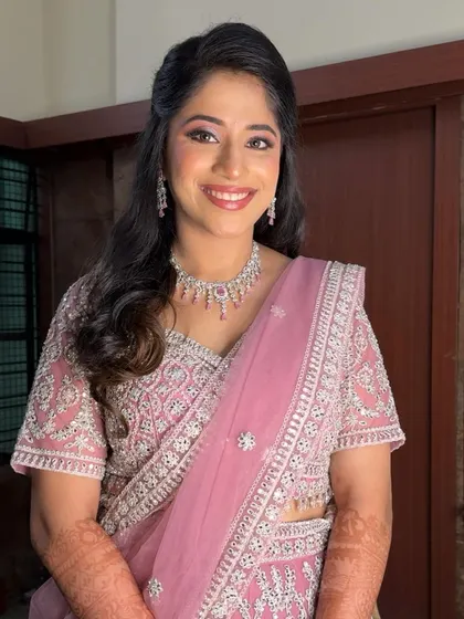 A smiling shot of Harshitha, looking radiant for her reception. The pink tones in her makeup beautifully match her embroidered lehenga.