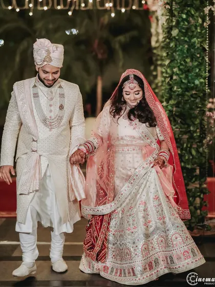 The couple walks together, the bride holding her lehenga, sharing a happy moment. These candid walking shots add life to the wedding album.