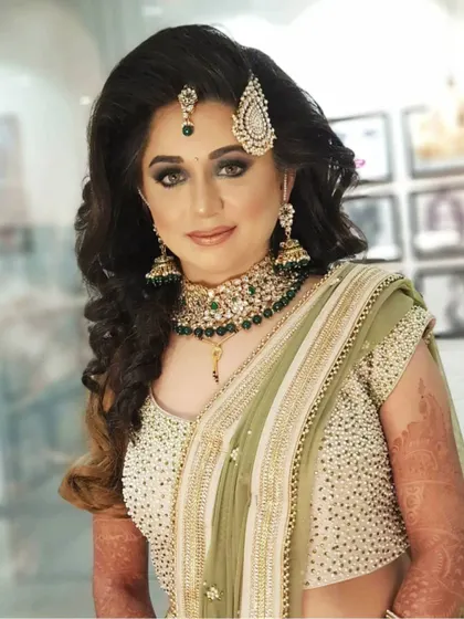 Your reception look should be just as stunning as your wedding day makeup. For this bride, we chose a glamorous smokey eye and a soft nude lip to match her elegant green saree. Her hair was styled in voluminous waves, creating a modern and chic look for her evening celebration.