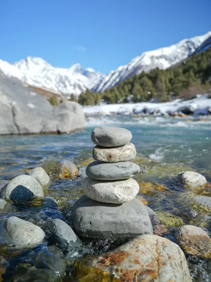A series of photos capturing the serene beauty of a river flowing through a snow-lined valley. The long-exposure shot creates a milky effect on the water, contrasting with the sharp peaks.