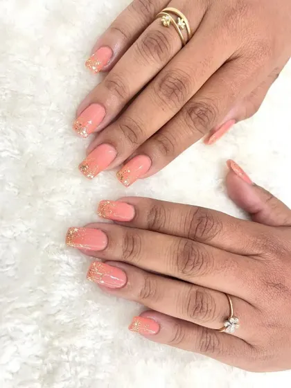 A beautiful shot of these pastel peach nails with gold glitter tips. This design offers a perfect balance of color and sparkle, ideal for a bride who wants a softer look.