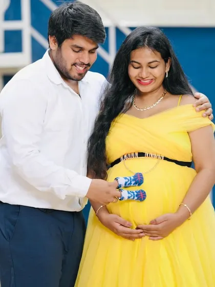 A playful hint at what's to come. The couple holds up tiny baby socks against the bump, a sweet detail for any maternity photoshoot. Our rental outfits provide the perfect canvas for these personal and memorable moments.