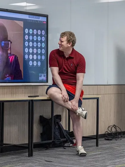 A moment of interaction between an in-person trainer and an online speaker during a hybrid session at the 2024 conference.