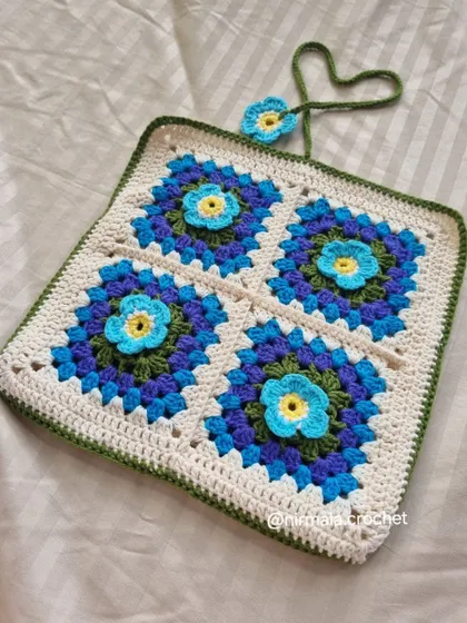 A full view of the 3D flower book sleeve, showing the four vibrant floral granny squares.
