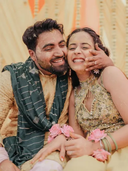 A heartwarming photo of the couple embracing, their faces smeared with haldi and lit up with genuine smiles.