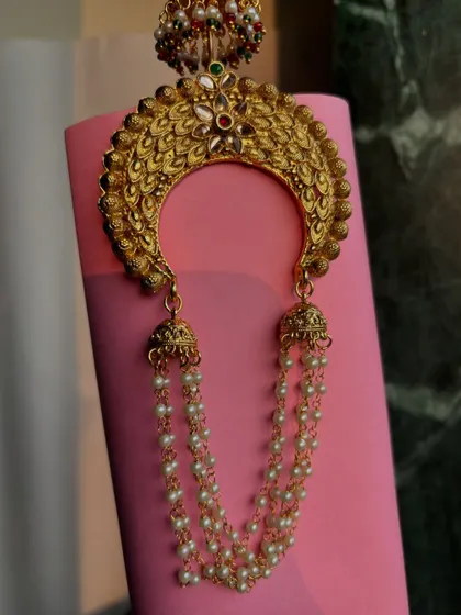 A close-up of the crescent-shaped khopa, showing the intricate design and the small jhumkas at the top.