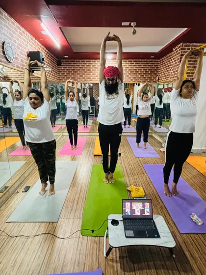 Students in Tadasana Urdhva Baddhanguliyasana, a standing stretch, during our Yoga Day class. The synchronized movement creates a beautiful, collective energy.
