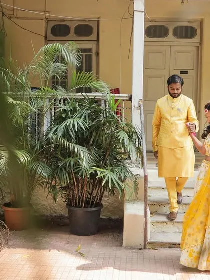 A candid shot of the couple walking down the steps of a beautiful old house for their Haldi ceremony. The framing adds a nice touch.