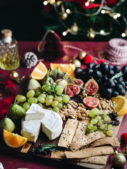 A beautiful Christmas-themed cheese board. The abundance of fresh fruit, cheese, and festive decorations creates an image of holiday indulgence and joyful gatherings.