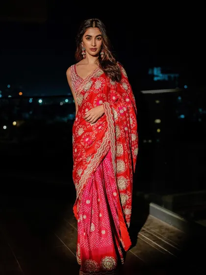 The stunning Pooja Hegde in a traditional red and pink bandhani saree with heavy embroidery. This is a perfect example of a classic, regal look for a major festive event.