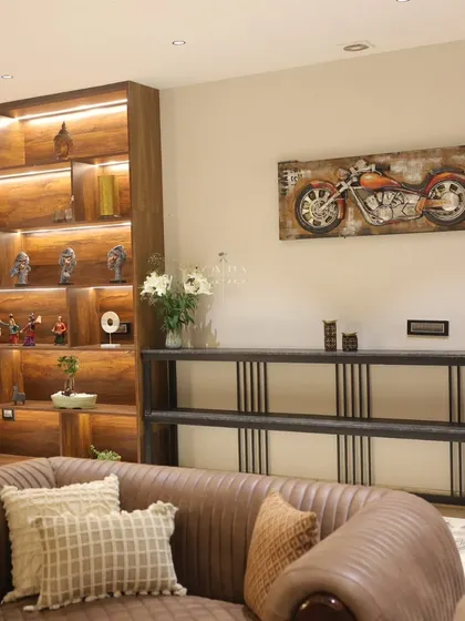 Open wooden shelves with subtle profile lighting proudly showcase the client's collection, while a motorcycle art piece adds a personal touch.