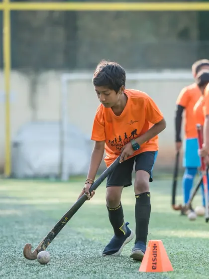 A young player practicing ball control around cones. This fundamental drill is crucial for developing the fine motor skills and coordination needed for advanced hockey techniques.