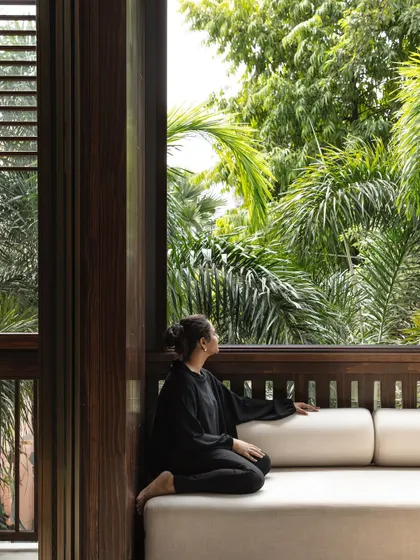 A quiet moment in a 'jharokha', a modern interpretation of the traditional enclosed balcony. These spaces are designed as intimate nooks for contemplation, connecting the resident with the outdoors while maintaining privacy.