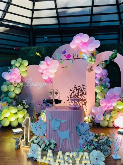 A soft pink enchanted forest theme with deer props, birds, and butterflies for a first birthday.