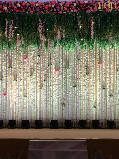 A full view of the stage backdrop, featuring a wall of white flowers with pops of pink, creating a fresh and vibrant look.