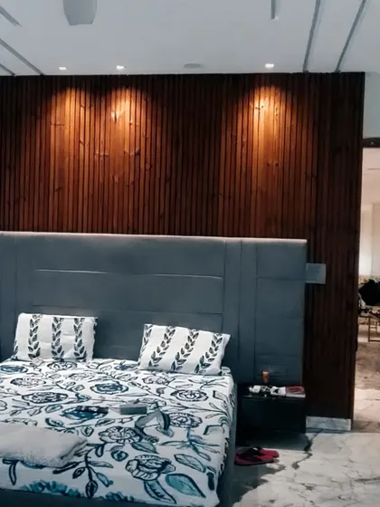 A finished bedroom with a floor-to-ceiling wood-paneled accent wall. The spotlights are strategically placed to highlight the texture of the wood, creating a warm and inviting focal point in the room.