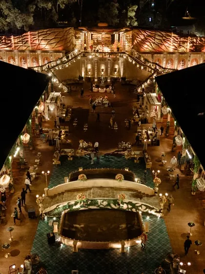 An aerial view of the venue at night, showing the main garden, the Roman bridge, and the surrounding structures all illuminated. This shot captures the complexity and scale of the world we built.