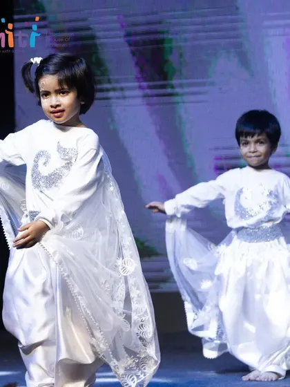 Two young performers dance together, their costumes evoking the lightness and movement of air.