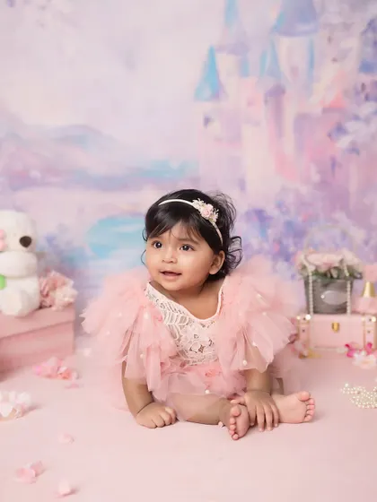 Looking off into the distance, perhaps dreaming of her next royal adventure. The fairytale backdrop adds a touch of magic to this milestone photo.
